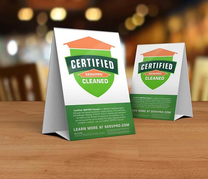 table tent signs describing the Certified: SERVPRO Cleaned program on top of wooden table top
